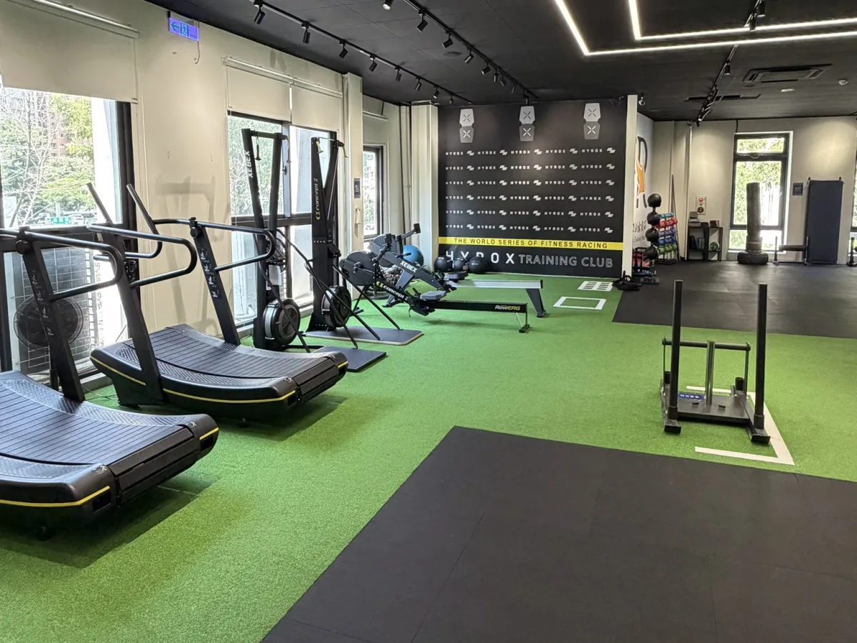 HYROX 專區,弧形跑步機、滑步機與雪橇道,牆面是 HYROX Training Club 標識